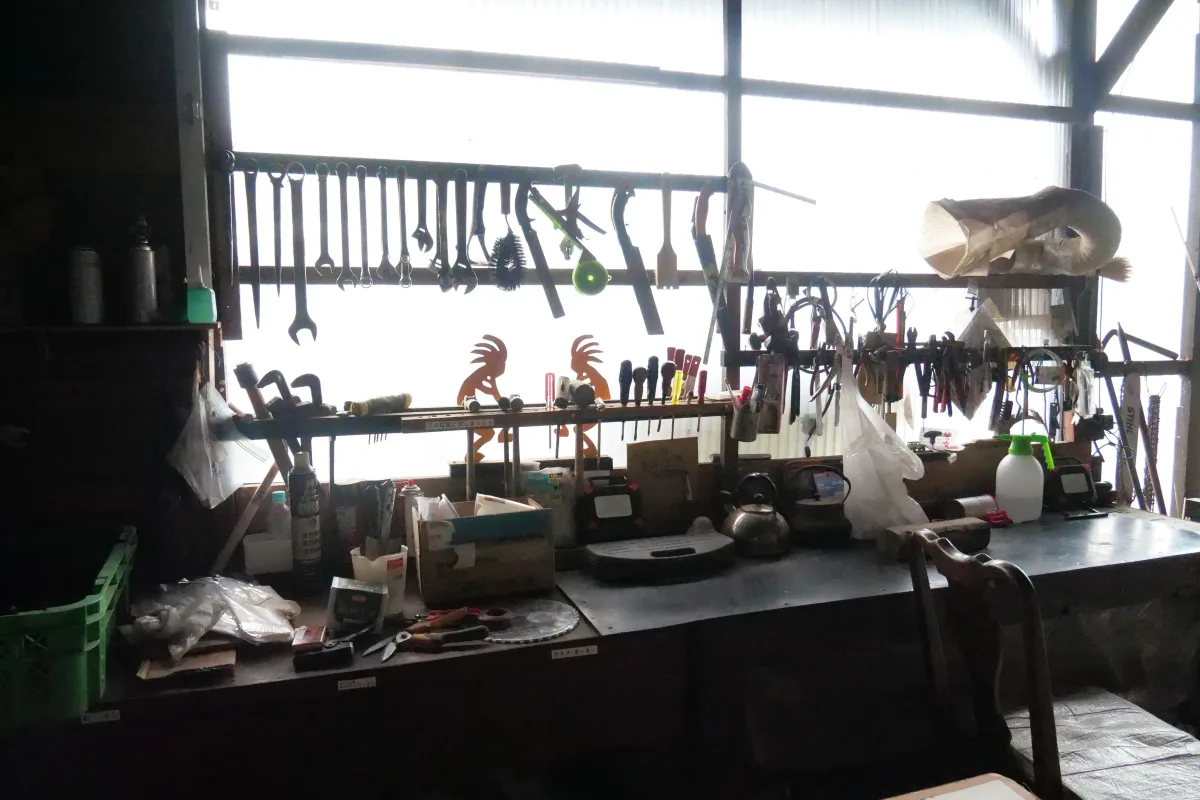 農具が掛けられた壁と道具が並ぶ作業台